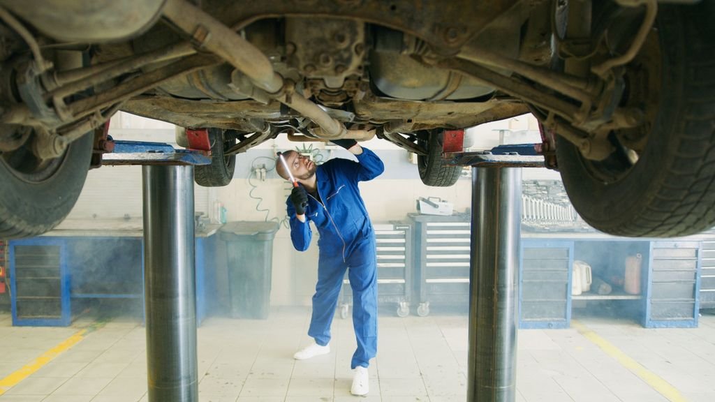 Mechanic inspecting a vehicle raised on a lift inside a garage